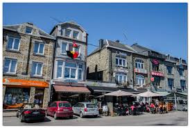Rue animée de Bertrix avec camion débouchage devant bâtiment typique. Débouchage Bertrix en action dans la ville.