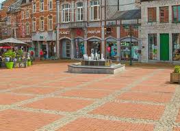 Débouchage Marche-en-Famenne rue animée avec maisons en pierre, boutiques locales et piétons profitant d'une belle journée.