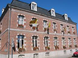 Rue pittoresque de Silly avec panneau Débouchage Silly, maisons en briques rouges et végétation luxuriante.