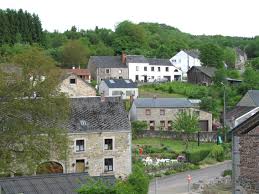Débouchage Tellin rue idyllique avec maisons en pierre et collines verdoyantes, typique de l'atmosphère paisible de la ville.