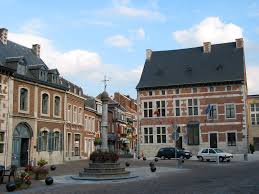 Scène urbaine à Theux avec plombier en action près de la fontaine de l’Ourdische dans une rue typique de la ville.