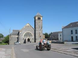 Plombier Vaux-sur-Sûre devant l'église locale, rues pavées et maisons traditionnelles en arrière-plan.