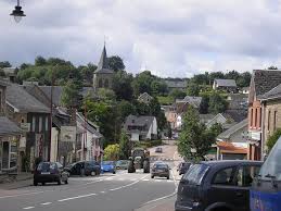 Plombier Waimes dans rue pavée pittoresque avec maisons en pierre et église historique en arrière-plan