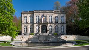 Plombier Auderghem devant une maison bruxelloise typique, avec rues pavées et verdure en arrière-plan, scène locale dynamique