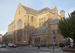 Plombier Berchem Sainte Agathe devant l'église St-Martin, rue pavée avec commerces typiques et ambiance locale.