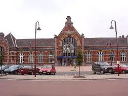 Rue animée de Châtelet avec entreprise de vidange fosse septique, façade en briques rouges et lampadaires typiques.