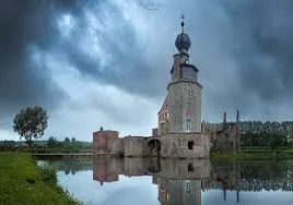 Plombier urgence Colfontaine van passant devant maison en briques rouges typiques de la région, rue calme et arborée