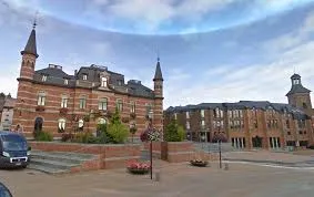 Scène d'un plombier urgence Frameries devant l'hôtel de ville, bâtiment emblématique avec architecture traditionnelle.