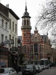 Plombier Jette réparant une canalisation près de l'Église Saint-Pierre au cœur de la ville animée avec ses rues pavées.