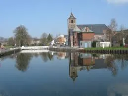 Plombier La Louvière devant l'hôtel de ville art déco et une statue en plein centre-ville animé.