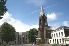 Vidange fosse septique Manage rue animée avec commerces, bâtiments en briques et trottoirs bordés d'arbres