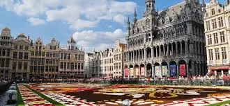 Plombier urgence Mouscron devant l'église Saint-Barthélemy, scène urbaine animée de passants et commerces locaux.