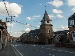 Scène urbaine à Oupeye avec vue sur un camion de service Débouchage Oupeye devant des maisons typiques de la ville.